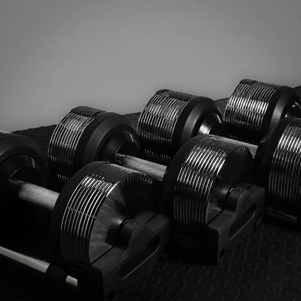 Set of black dumbbells on a dark surface with a neutral background