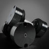 Pair of black dumbbells with metallic finish on a dark surface