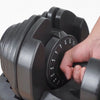 Hand adjusting a black adjustable dumbbell on a white background