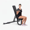 Woman exercising with dumbbells on a weight bench against a white background