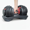 Adjustable dumbbell set with a hand holding one of the weights on a white background