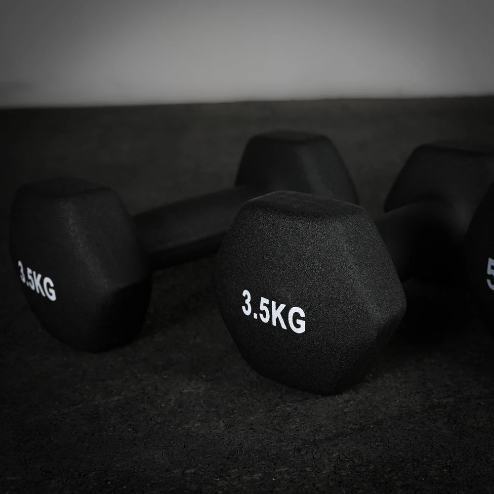 Pair of black dumbbells with '3.5KG' marking on a dark surface