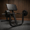 Black weight bench with weights on a dark floor against a light wall