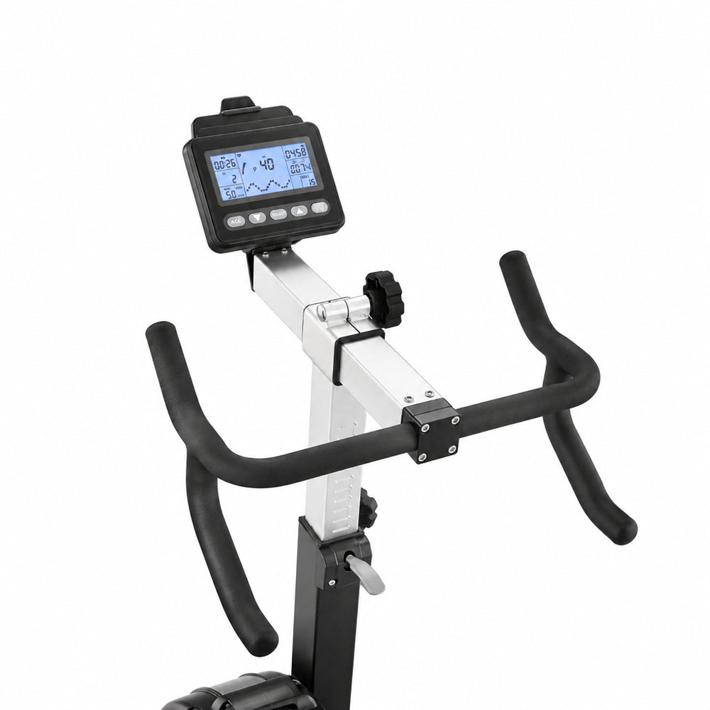 A close-up of a fitness exercise bike's handlebar assembly, featuring black curved grips, a silver metal frame, and a black digital display screen mounted on the handlebar stem, set against a plain white background.
