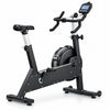 A black and silver indoor stationary exercise bike with a digital display screen on the handlebars, shown from a three-quarter angle against a solid white background.