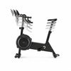 A black indoor cycling machine with a large front fan, black saddle, and multiple handlebar grips, shown on a clean white background.