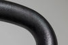 Close-up of a black metal handle on a gray background