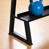 Close-up of a black metal weight bench with a blue kettlebell resting on the upper shelf, set on a light wood floor.