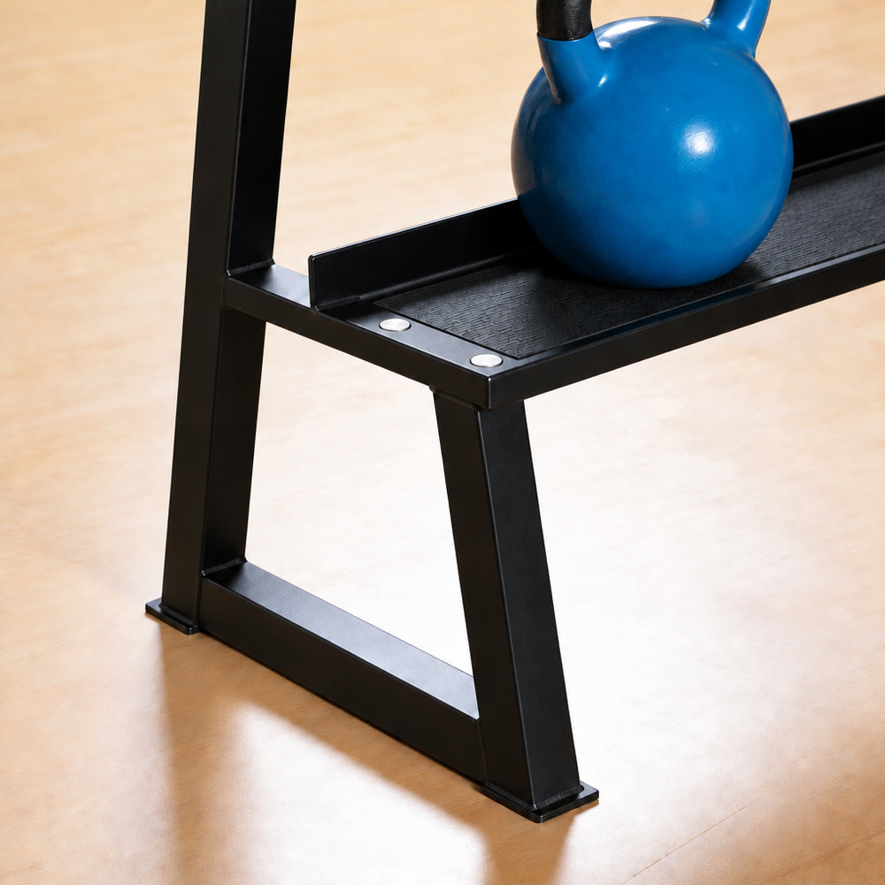 Close-up of a black metal weight bench with a blue kettlebell resting on the upper shelf, set on a light wood floor.