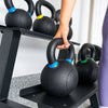 Person picking up a black kettlebell with blue accents off a kettlebell rack