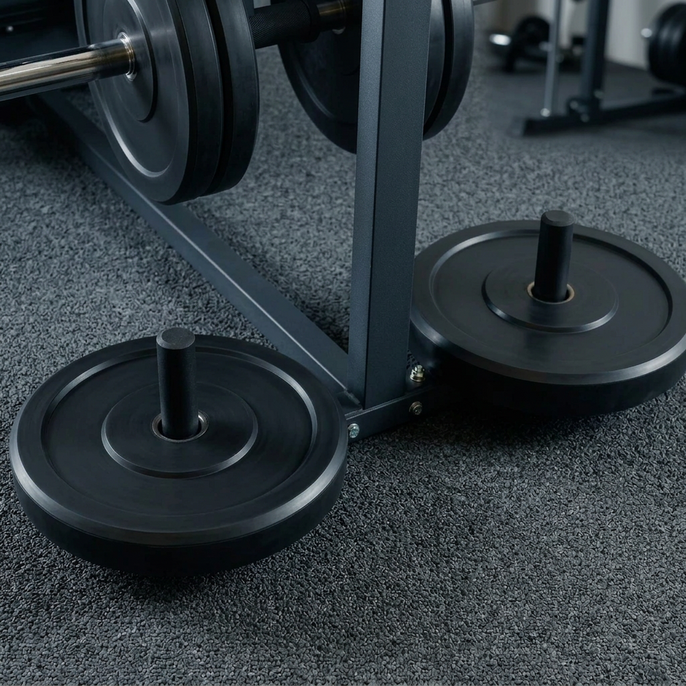 Close-up of a black metal weight bench frame with weight plates on the floor in a gym setting.