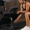 Woman adjusting a piece of gym equipment in a gym setting