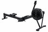 A black indoor rowing machine with a long rail, padded seat, footrest, and large circular flywheel on a stand, shown against a plain white background.