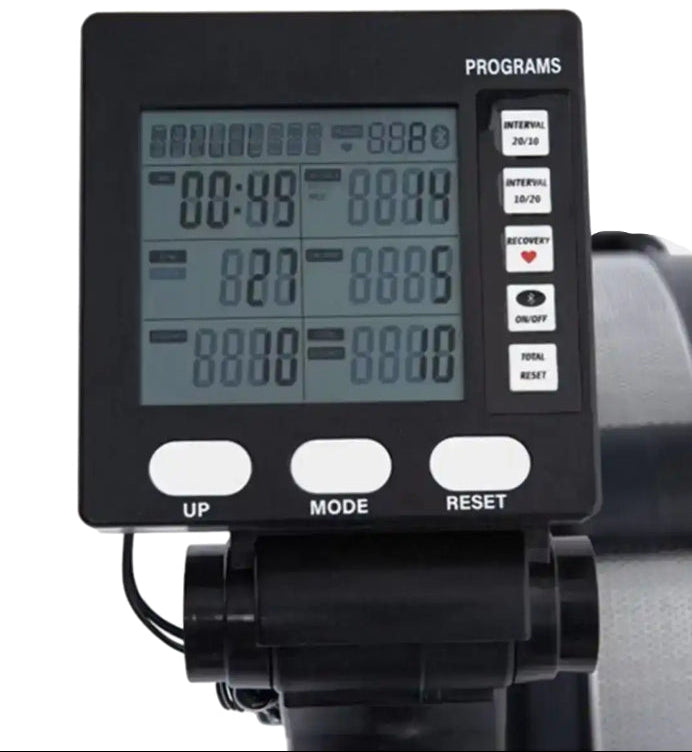 A close-up of a black digital exercise monitor display with buttons labeled UP, MODE, and RESET, mounted on a black handlebar or support structure against a white background.