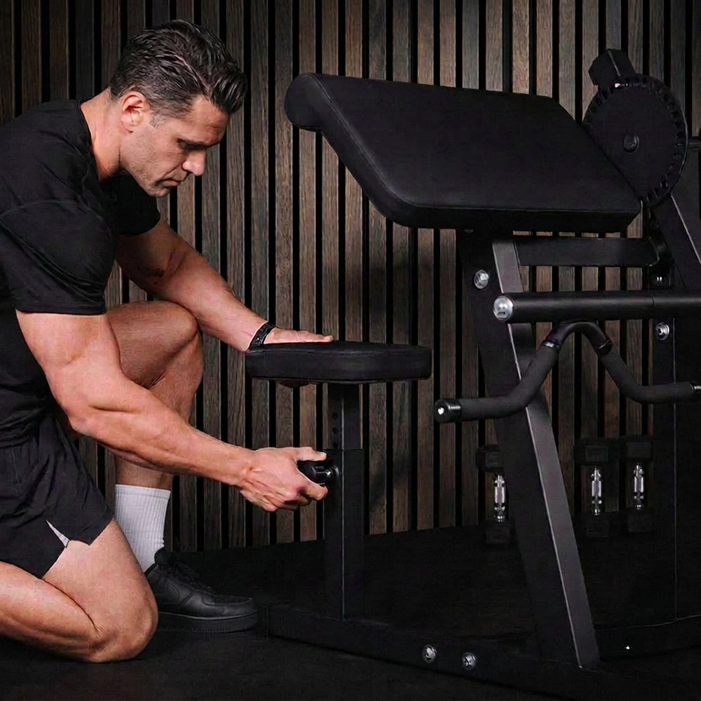 Man adjusting a gym machine in a dark setting