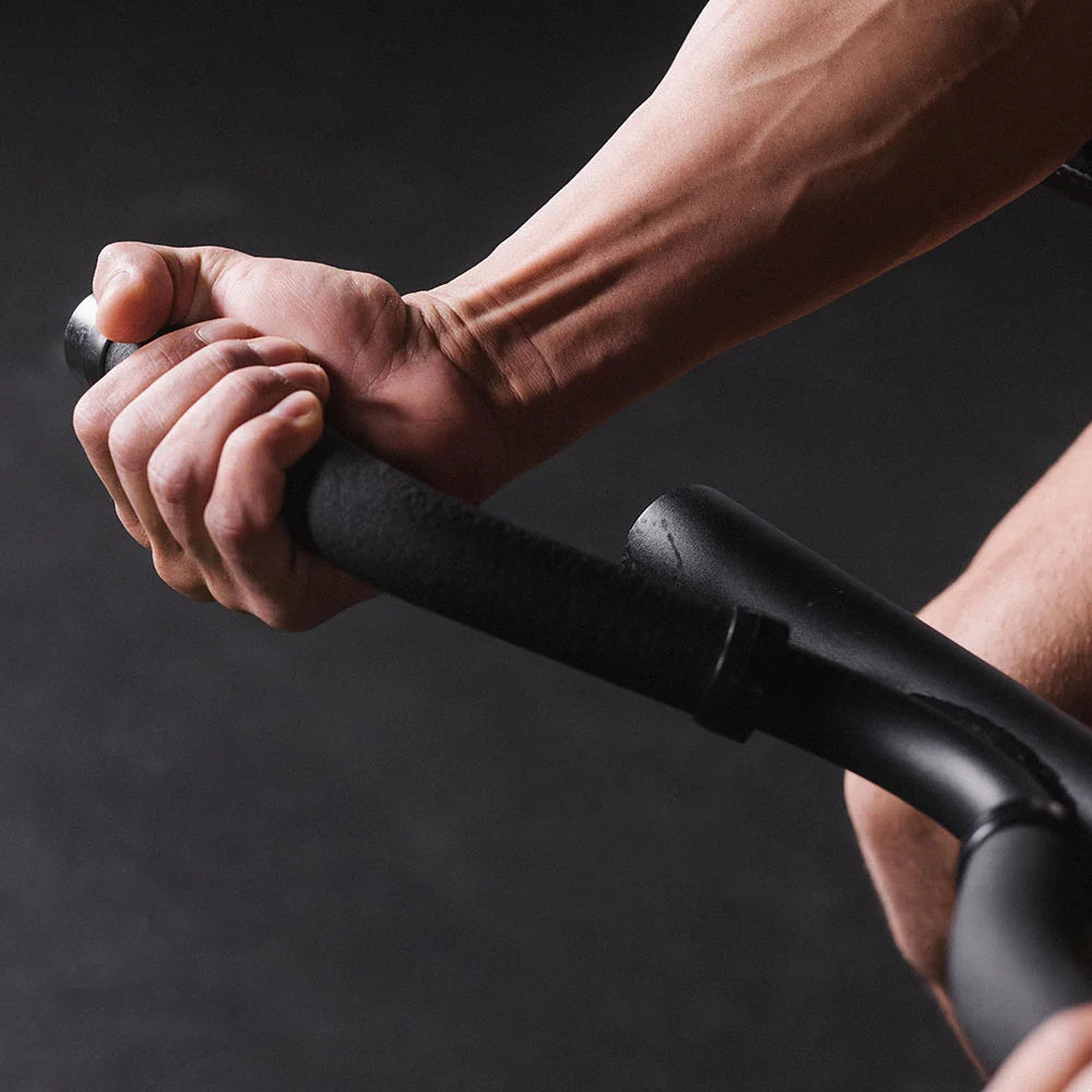 Close-up of a person's hand gripping a black handlebar against a dark background