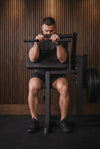 Person performing a squat exercise on a weight bench in a gym setting.