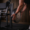 Person holding a black weight plate in a gym setting