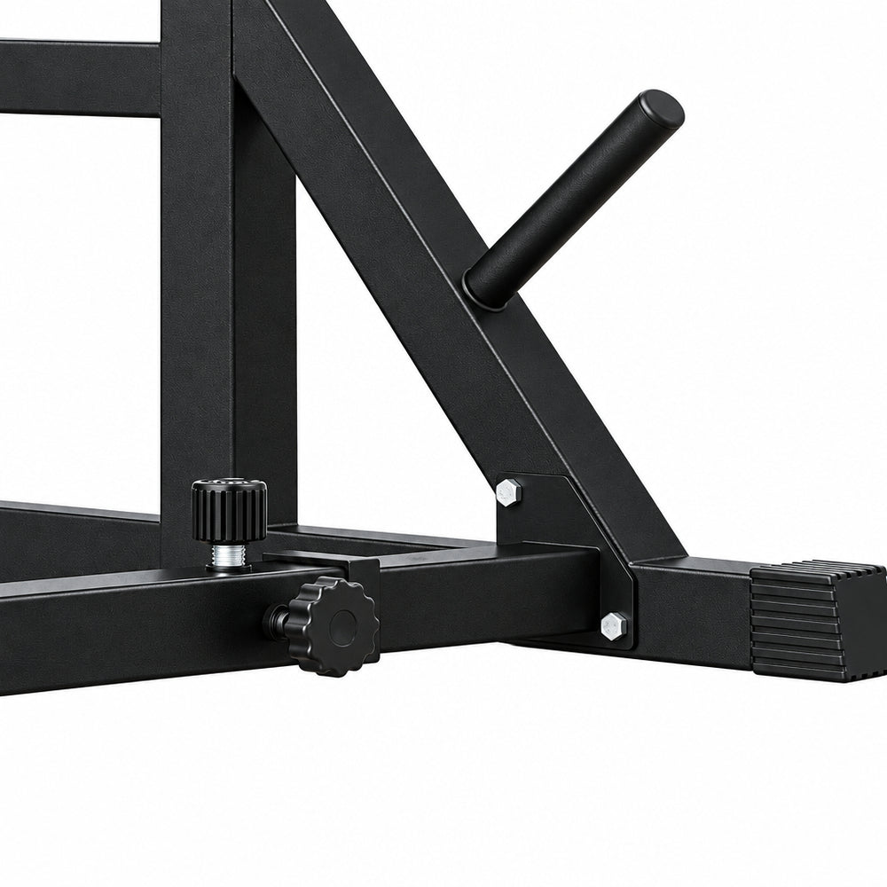 Close-up of a red and black metal weight bench frame with adjustment knobs and a black handle, shown on a light wood floor against a textured white wall.