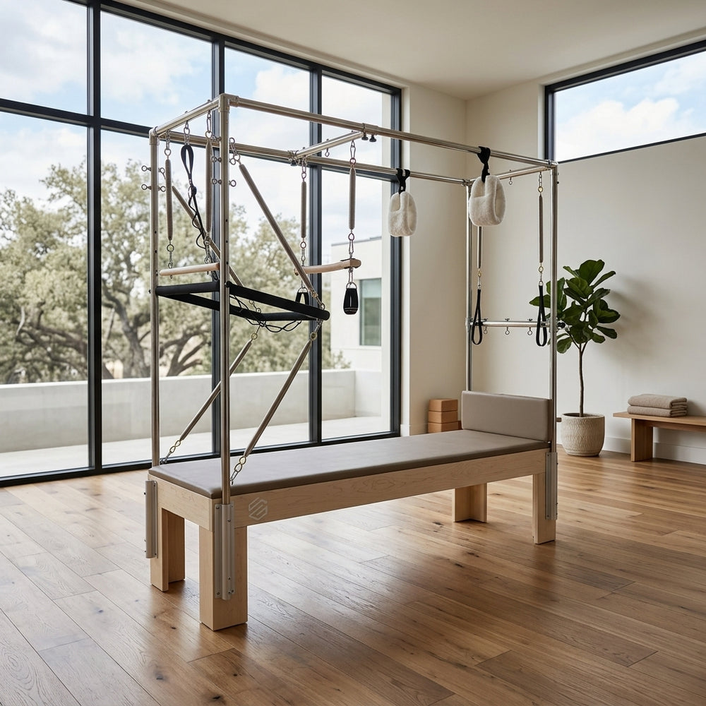 GS Essential Cadillac Reformer in light brown set up in a bright home Pilates studio