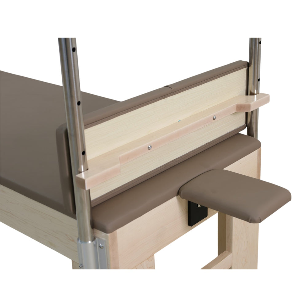 Close-up of the light wood footboard and padded armrest on the GS Essential Cadillac Reformer
