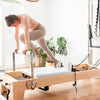 Women working out on an oak pilates reformer machine in a home gym setting