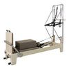 Gym Superstore professional wooden Pilates reformer with integrated tower attachment and grey padded carriage.